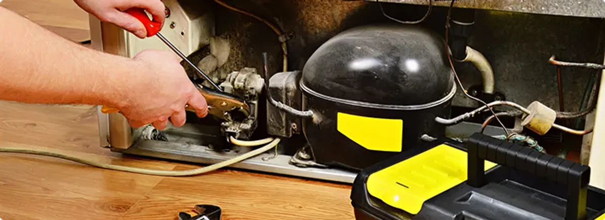 Refrigerator repair technician fixing the compressor and wiring in Sachse, TX