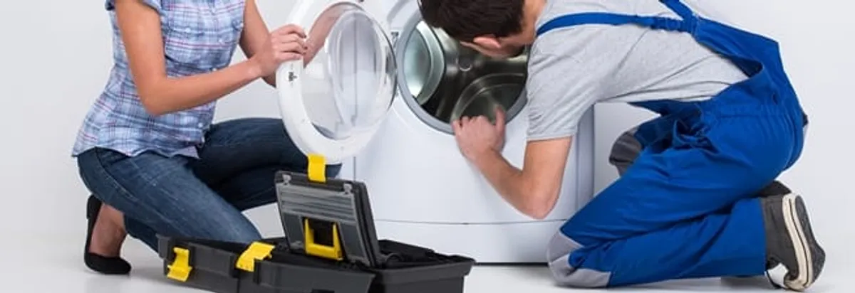 Washer repair technician inspecting a front-load washing machine with tools in Dallas, TX