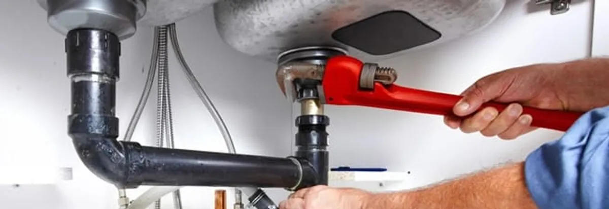 Garbage disposal repair technician tightening the sink drain and disposal connection in Dallas, TX
