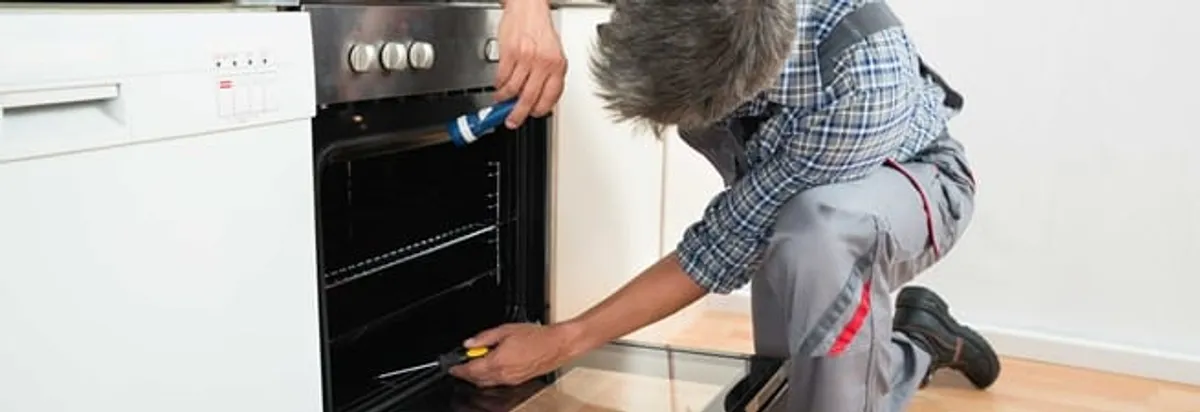 Oven repair technician inspecting and servicing an electric oven in Dallas, TX
