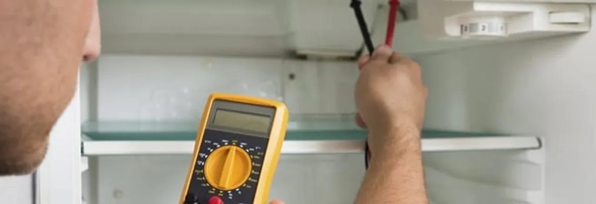 Refrigerator repair technician testing electrical components with a multimeter in Dallas, TX